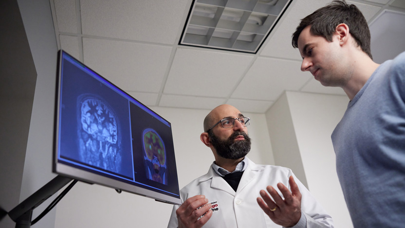 Neurologist Naoum Issa, MD looking at a brain scan with a male patient.