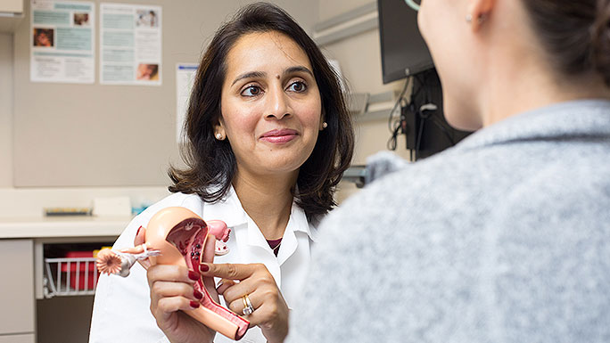 Gynecologist Maryam Siddiqui, MD, speaks with a patient, using a 3D anatomy model