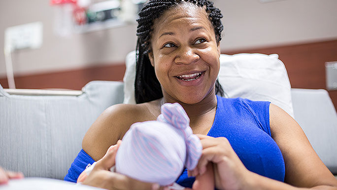 Smiling mom breastfeeds newborn