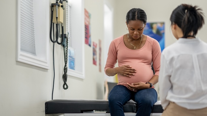 pregnant woman looking at belly at doctors office