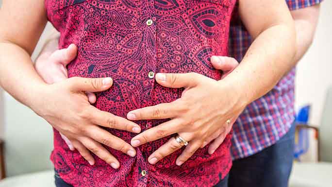 Parents' hands on pregnant belly