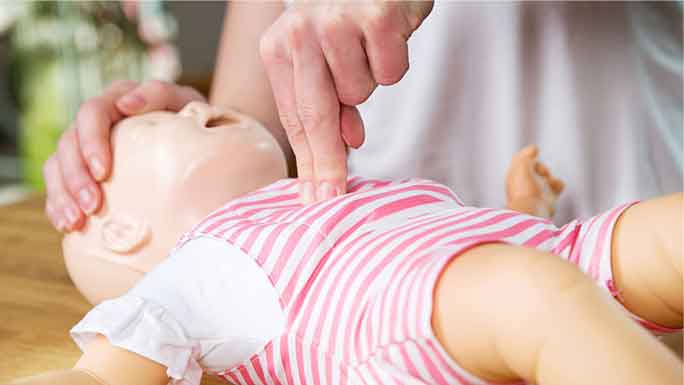 Fingers practice compressions on infant CPR doll