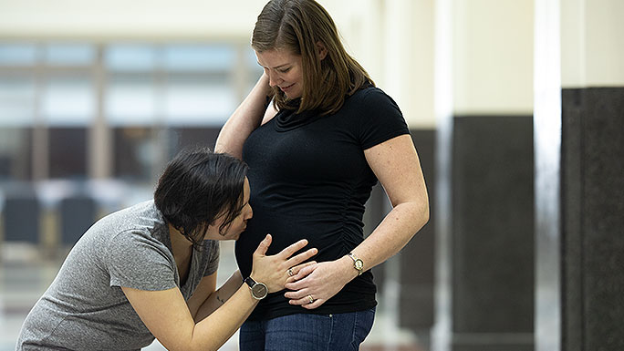 Woman kissing her partner's pregnant belly