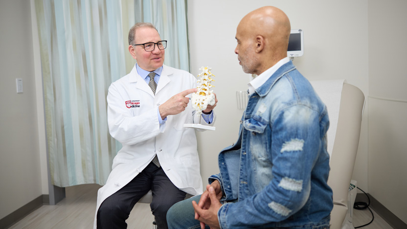  Spine surgeon Martin Herman, MD and a male patient in a clinic room 