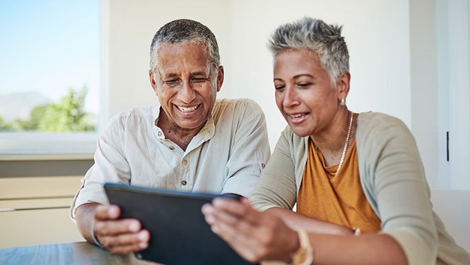 Senior couple smiling and looking at tablet