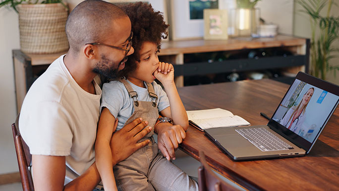 Father sits with son during on-demand virtual urgent care visit.