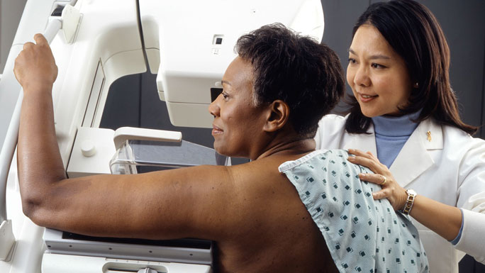 African American woman receiving mammogram, with female Asian tech. NCI image, Rhoda Baer (Photographer)
