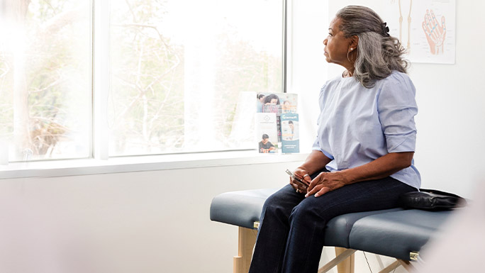 a woman sitting in a physician's office looking out the window