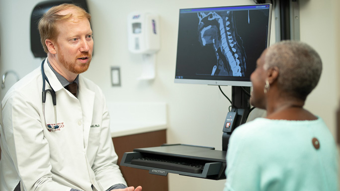 Alexander Pearson, MD, medical oncologist with patient and CT scan of neck