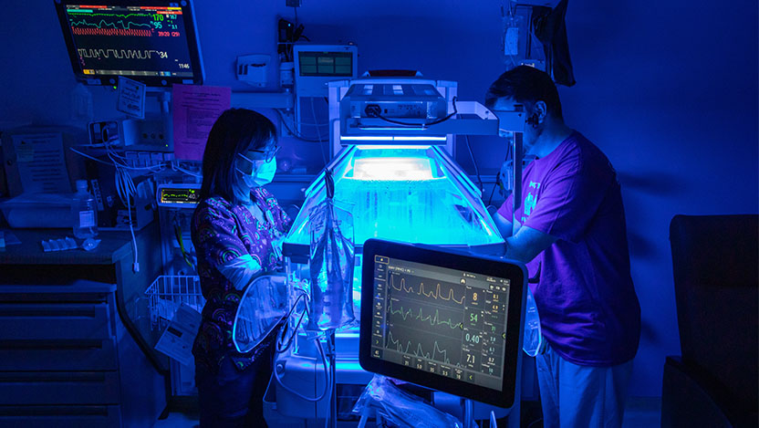 Image of nurse and parent working with baby in NICU small baby unit