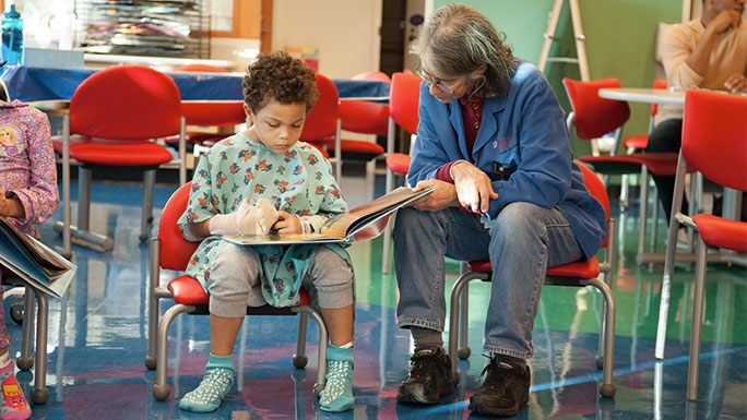 Comer volunteer reading with a patient