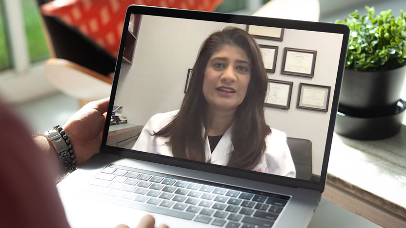 Male patient viewing laptop image of Sonali Smith, MD, giving a video visit