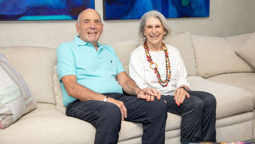 Susan and Ted Oppenheimer posing for a photo while sitting on a couch
