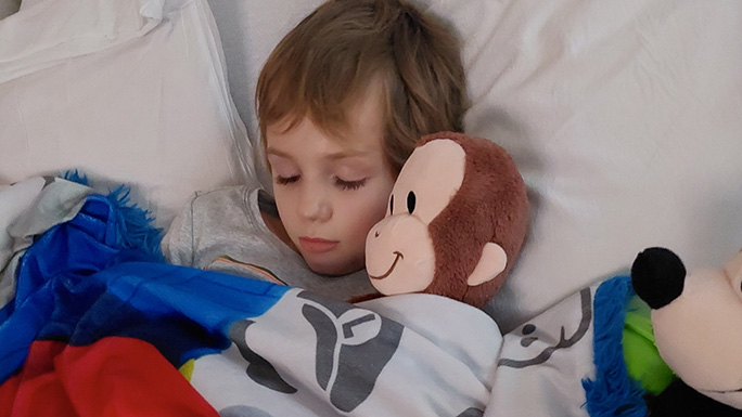 Image of pediatric neurosurgery patient Joseph Riofski cuddling with a toy monkey