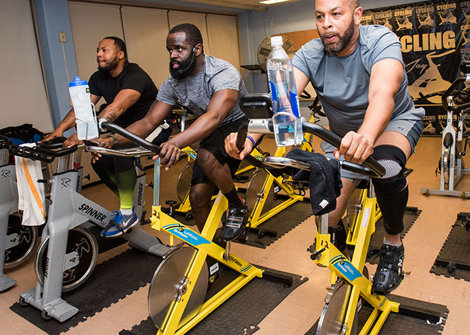 Men cycling in UHI South Side Fit program