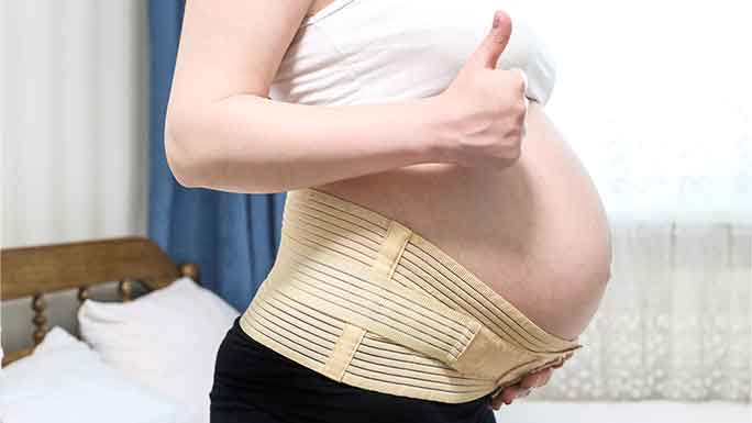 Pregnant belly in belly band or pregnancy support belt