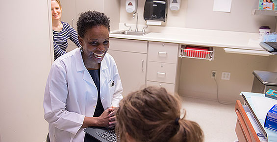 Pediatric and adolescent gynecologist Melissa Gilliam, MD, MPH, talks with a young patient while mom observes nearby
