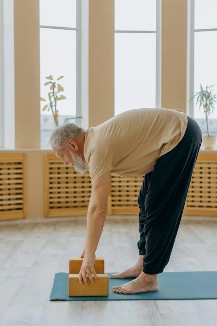 A man performs a forward fold while doing yoga.