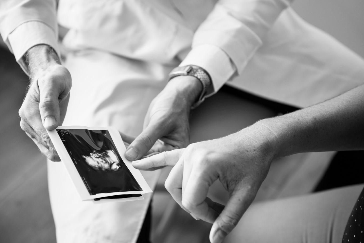 Two people sitting with an ultrasound image, pointing at the printout.
