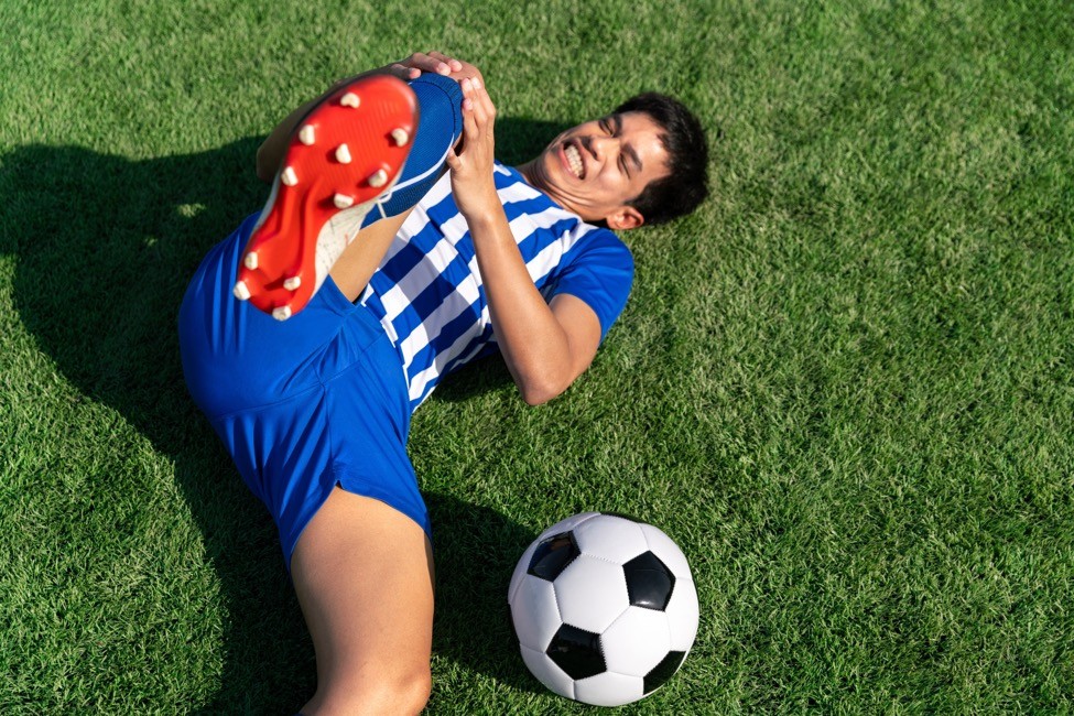 A young athlete grabs his knee in pain on the soccer field