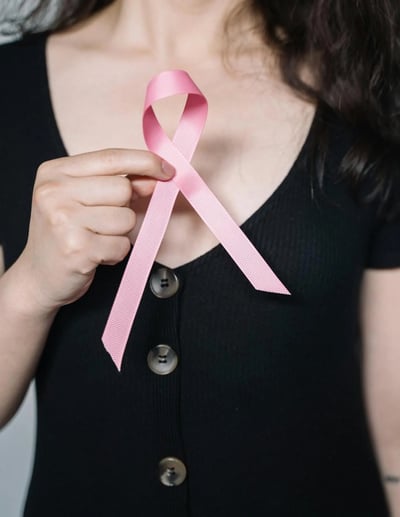 A person holds up a breast cancer awareness ribbon. 