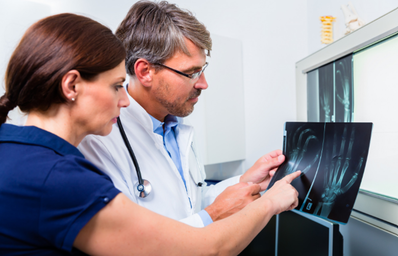 A physician reviewing orthopedic X-ray imaging with an adult patient during an evaluation.