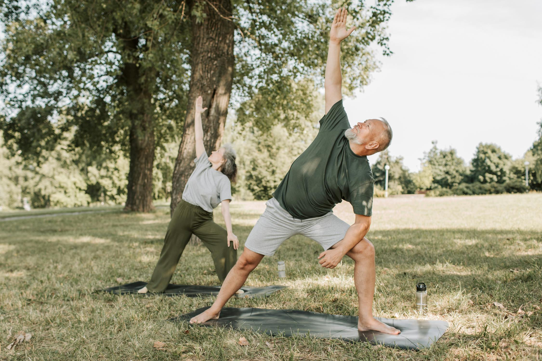 an elderly man and woman performing guided physical therapy exercises outdoors to aid recovery from a herniated disc