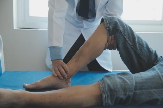 A podiatrist examining an adult patient's foot during an evaluation