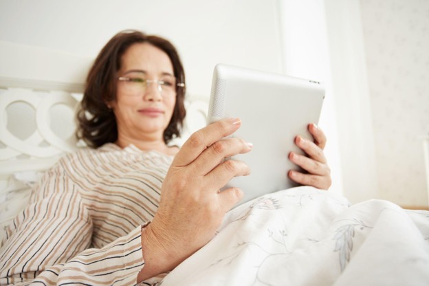 An adult reviewing information about an upcoming outpatient surgical procedure on a tablet at home