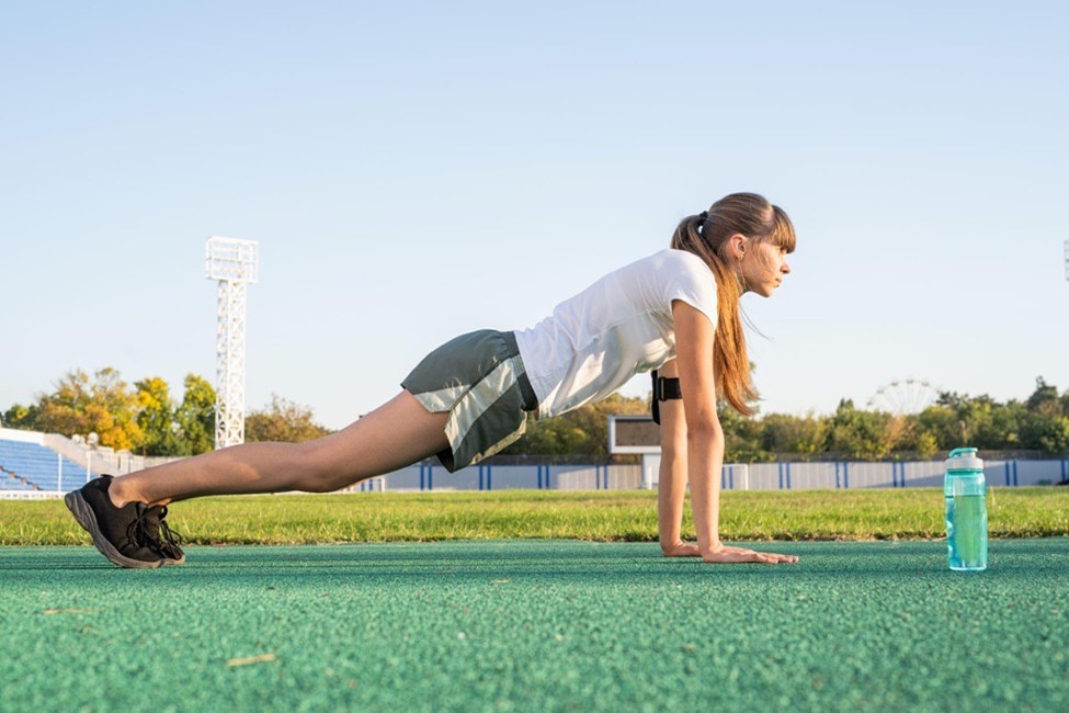 Teen athlete performing a plank exercise during outdoor sports training.