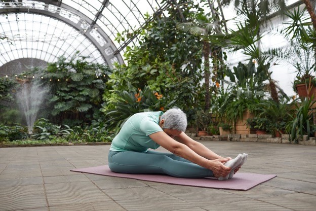 A woman stretches forward on a yoga mat.