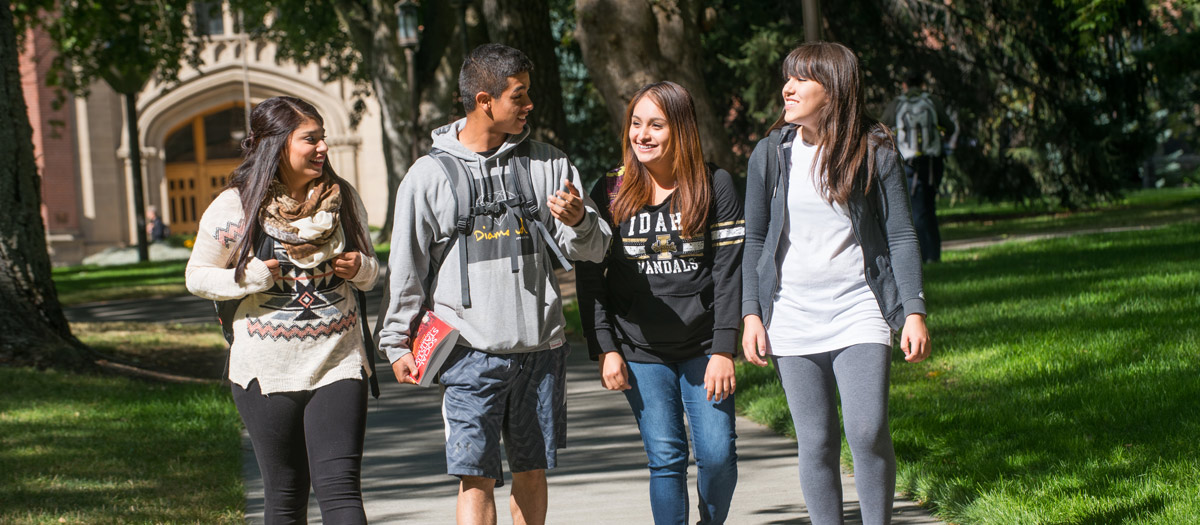 four college students walking on sidewalk