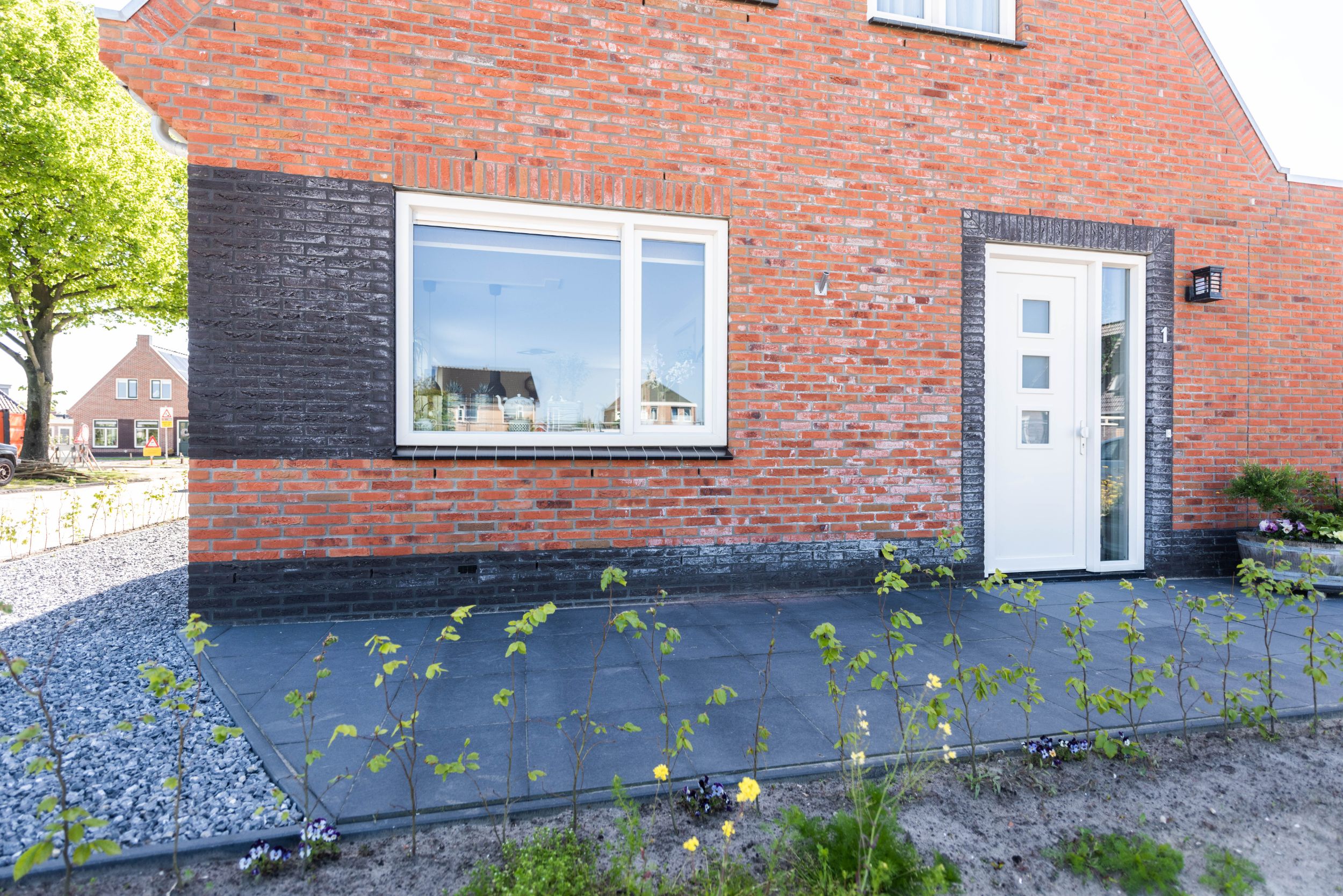 Detailfoto van de zijkant van een van de woningen in Akkrum. Je ziet een voordeur van de zijkant. 