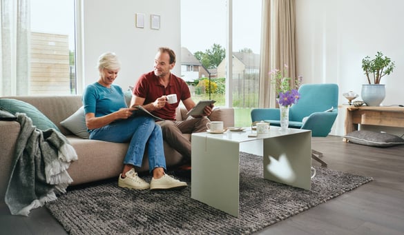 Senioren stel op de bank in de woonkamer met een kop koffie