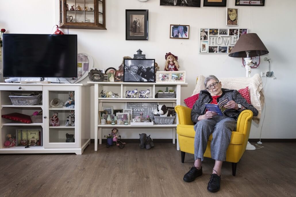 Oudere vrouw zit op een stoel in haar kamer