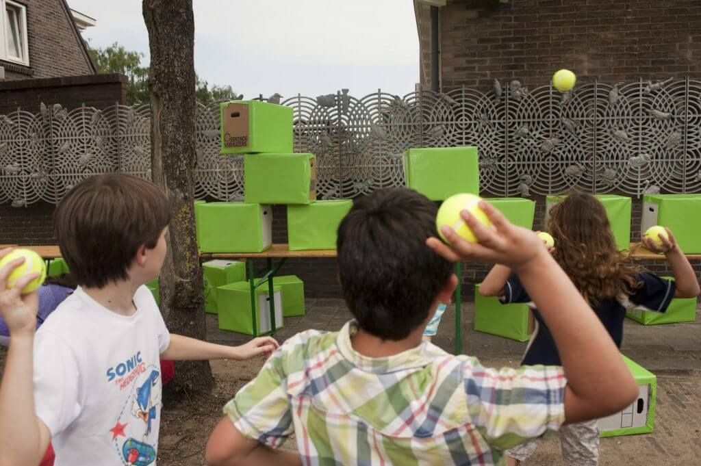 Kinderen gooien ballen tegen dozen