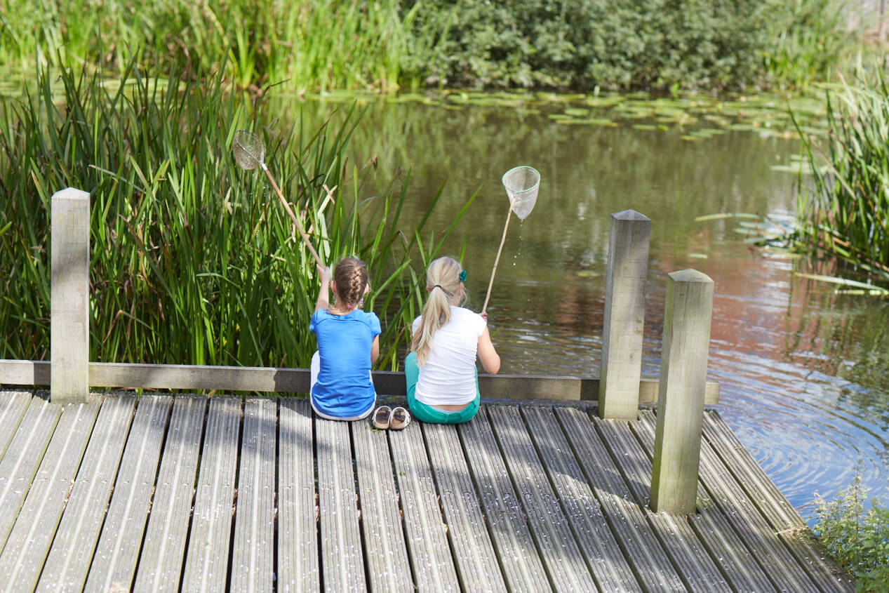Twee meisjes met visnet aan het water