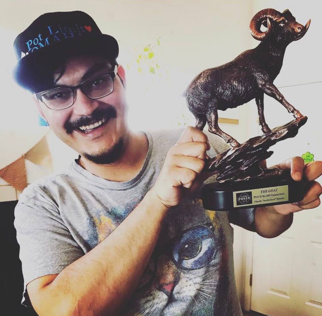 A person holding a trophy of a goat, awarded for poker performance, wearing a cat graphic t-shirt and a blurred cap