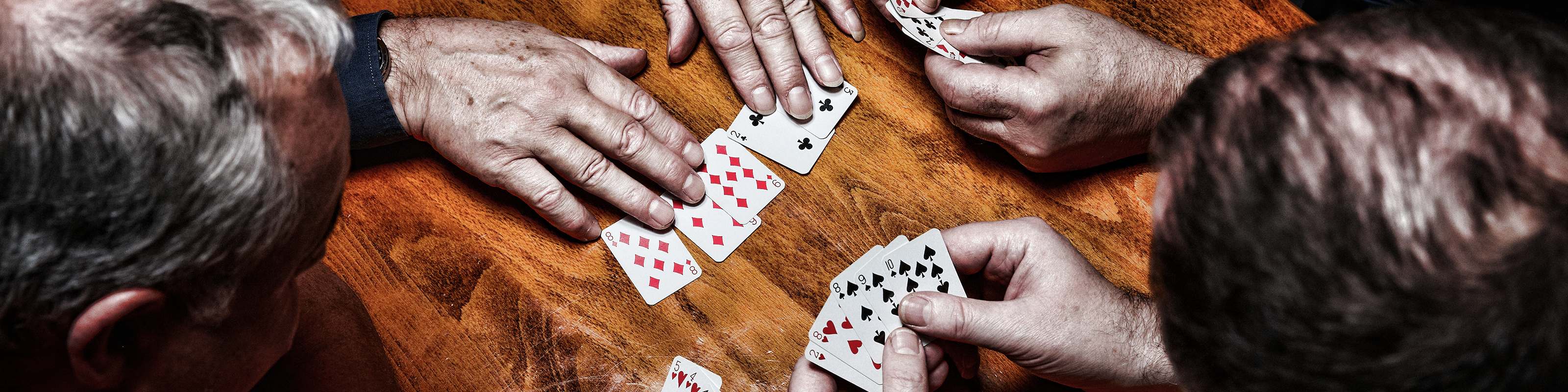 Close-up of hands holding playing cards on a wooden table