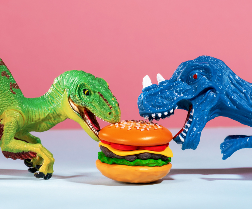 Toy dinosaurs fighting over burger