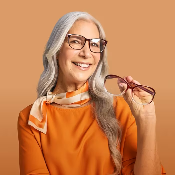 Woman wearing eyeglasses while holding another pair in her hand