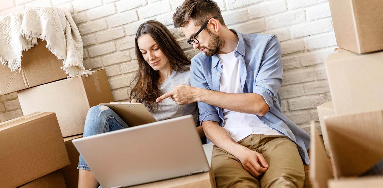Couple making moving checklist on laptop