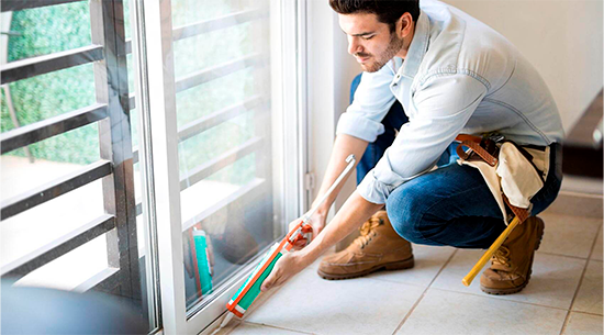 Man sealing door frame with caulk 