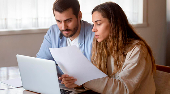 man and woman compare paper bill with laptop 