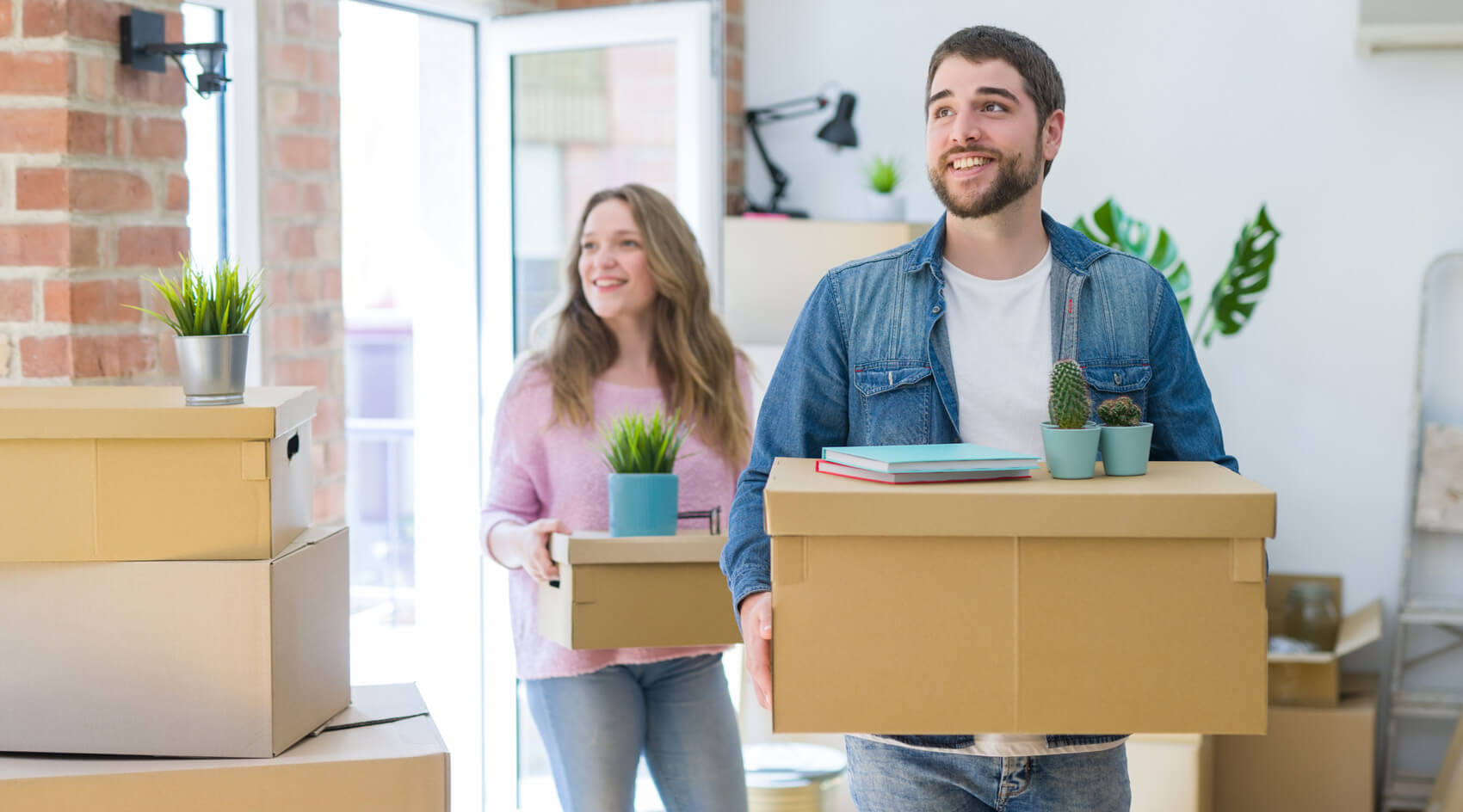 A young couple carries boxes into their new home