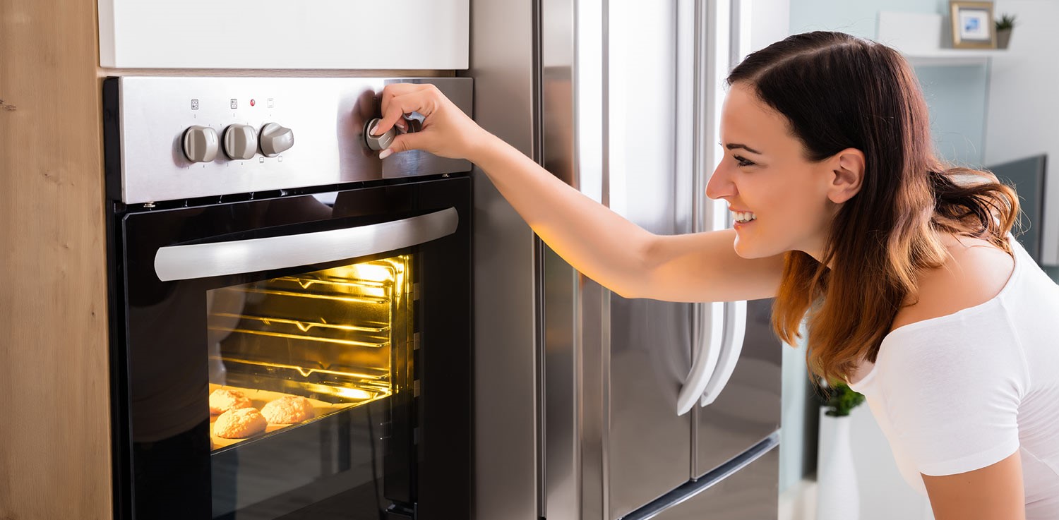 Woman adjusts the temperate dial on an electric oven