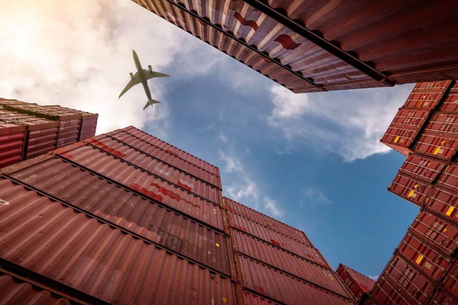 View of airplane surrounded by shipping containers