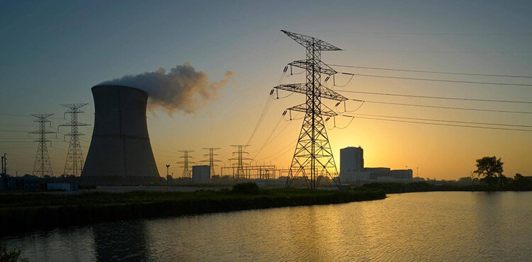 Cooling tower and power lines at sunset