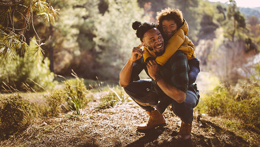 Father giving daughter piggyback ride on a hike