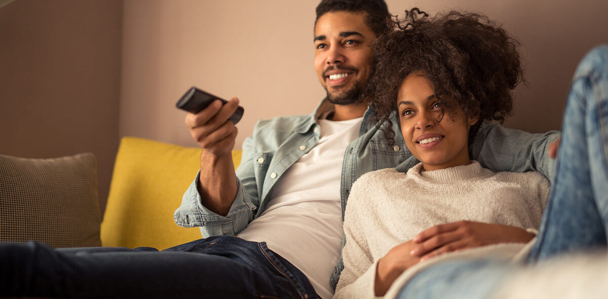 A couple on a couch with a remote control